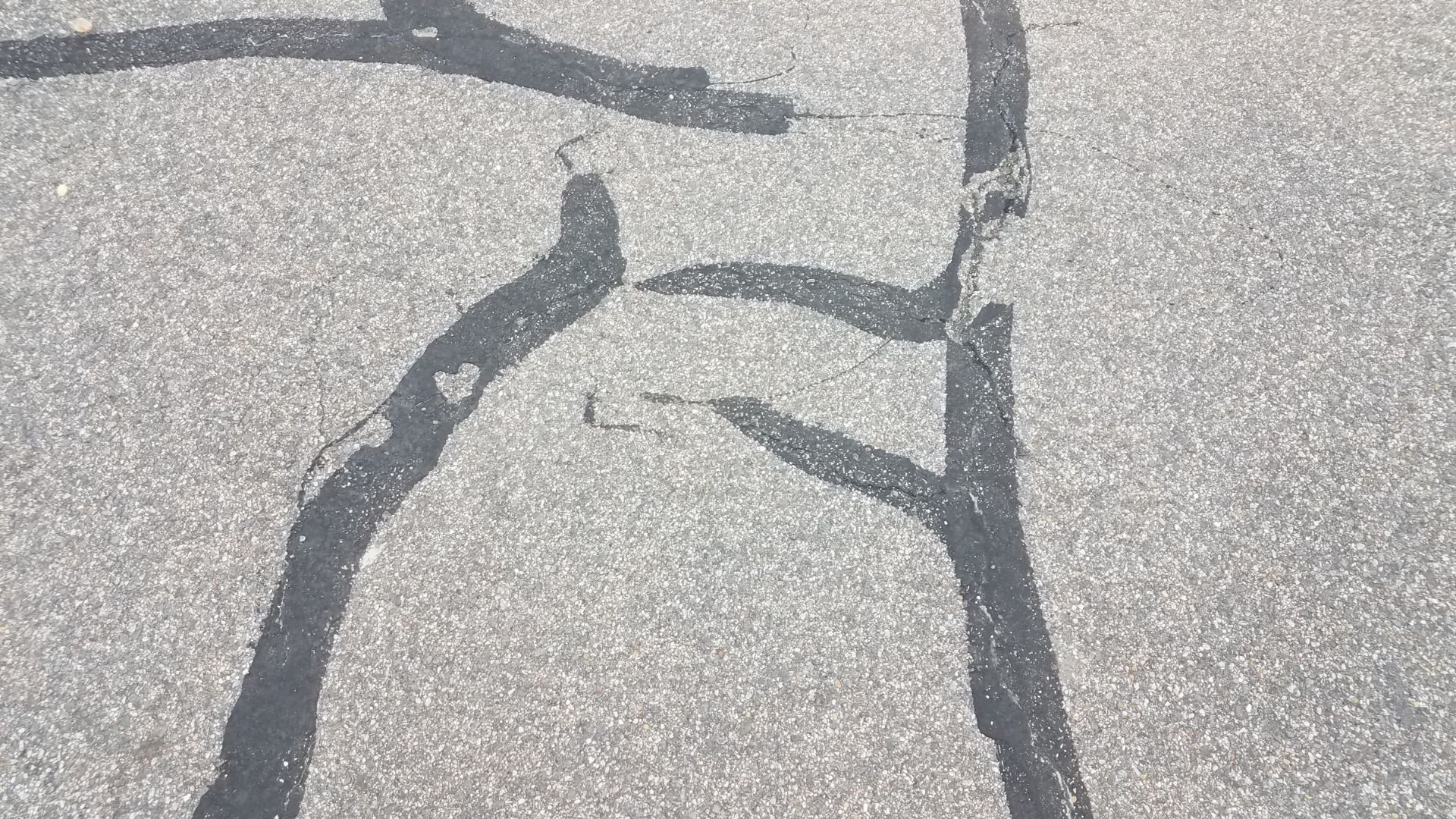 Cracked and weathered concrete surface with intersecting dark lines