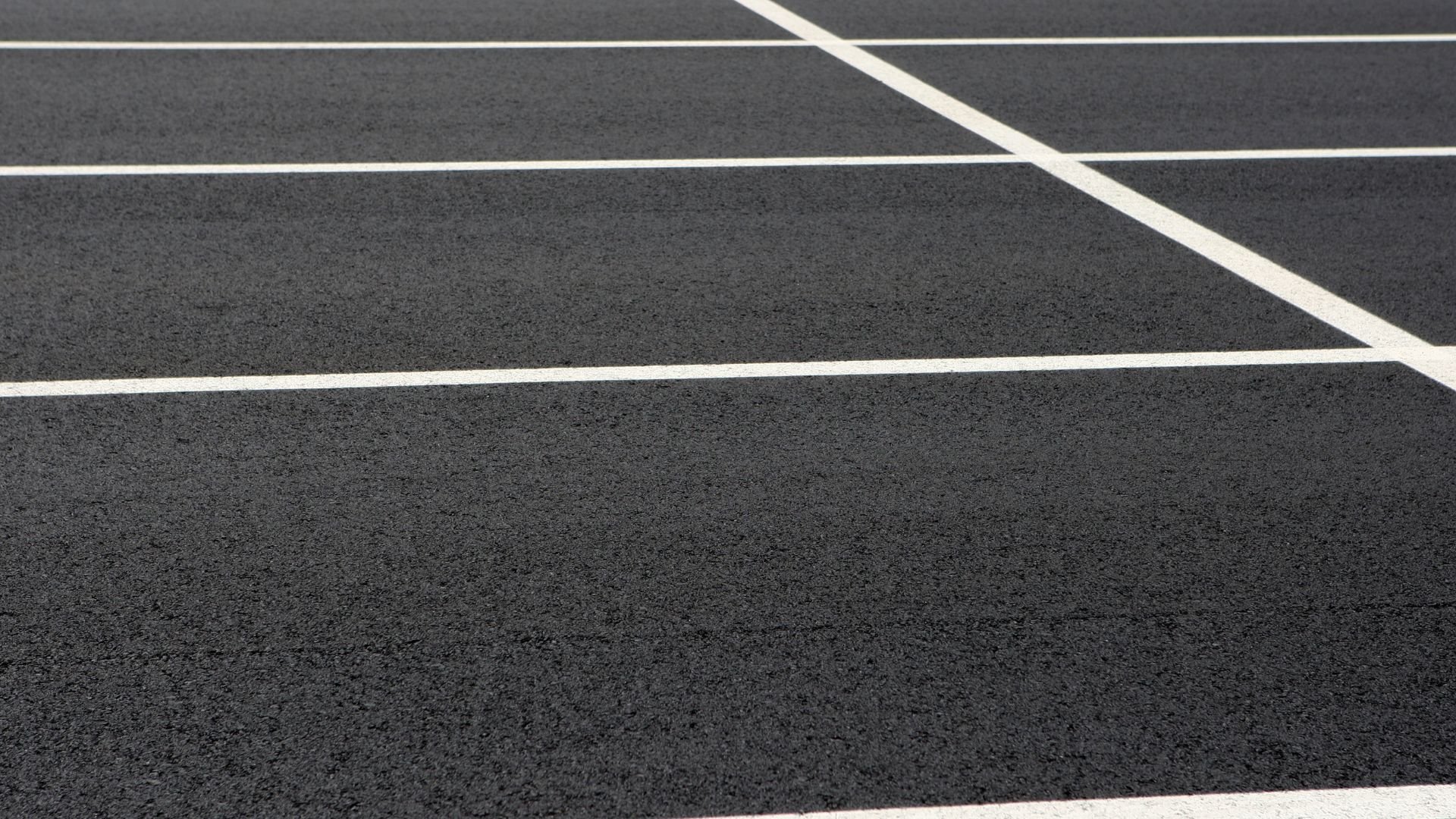 Tennis court with white lines on dark asphalt surface