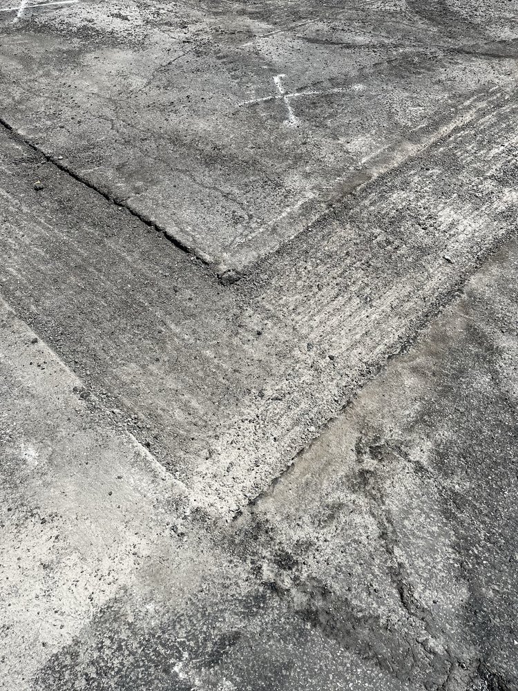 Worn concrete surface with intersecting diagonal lines and textured patterns