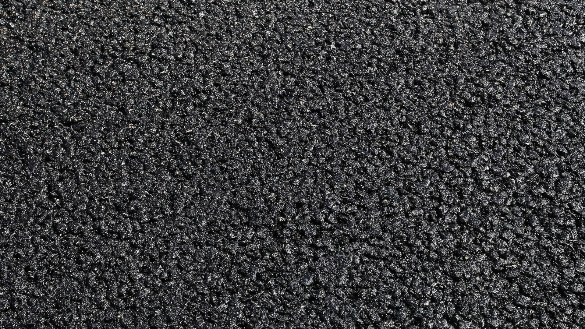 Dark asphalt or tarmac surface with fine textured rocky granules