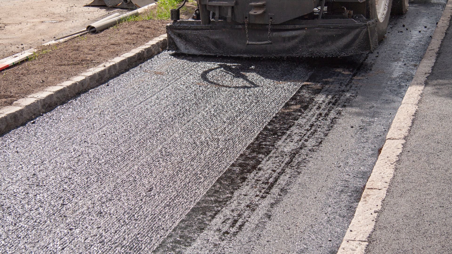 Asphalt paving machine laying fresh gray road surface