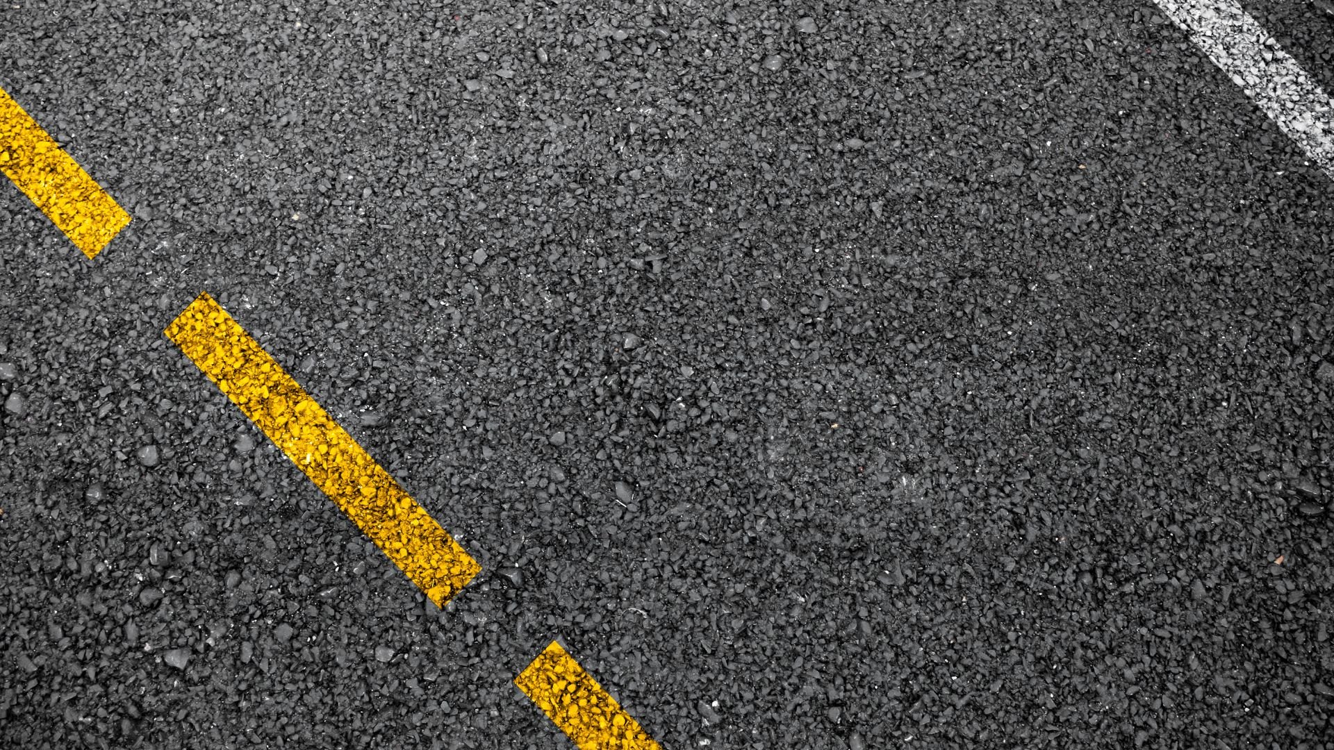 Yellow diagonal lines on textured asphalt road surface
